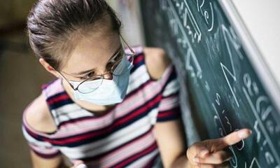 leerling met mondmasker aan bord